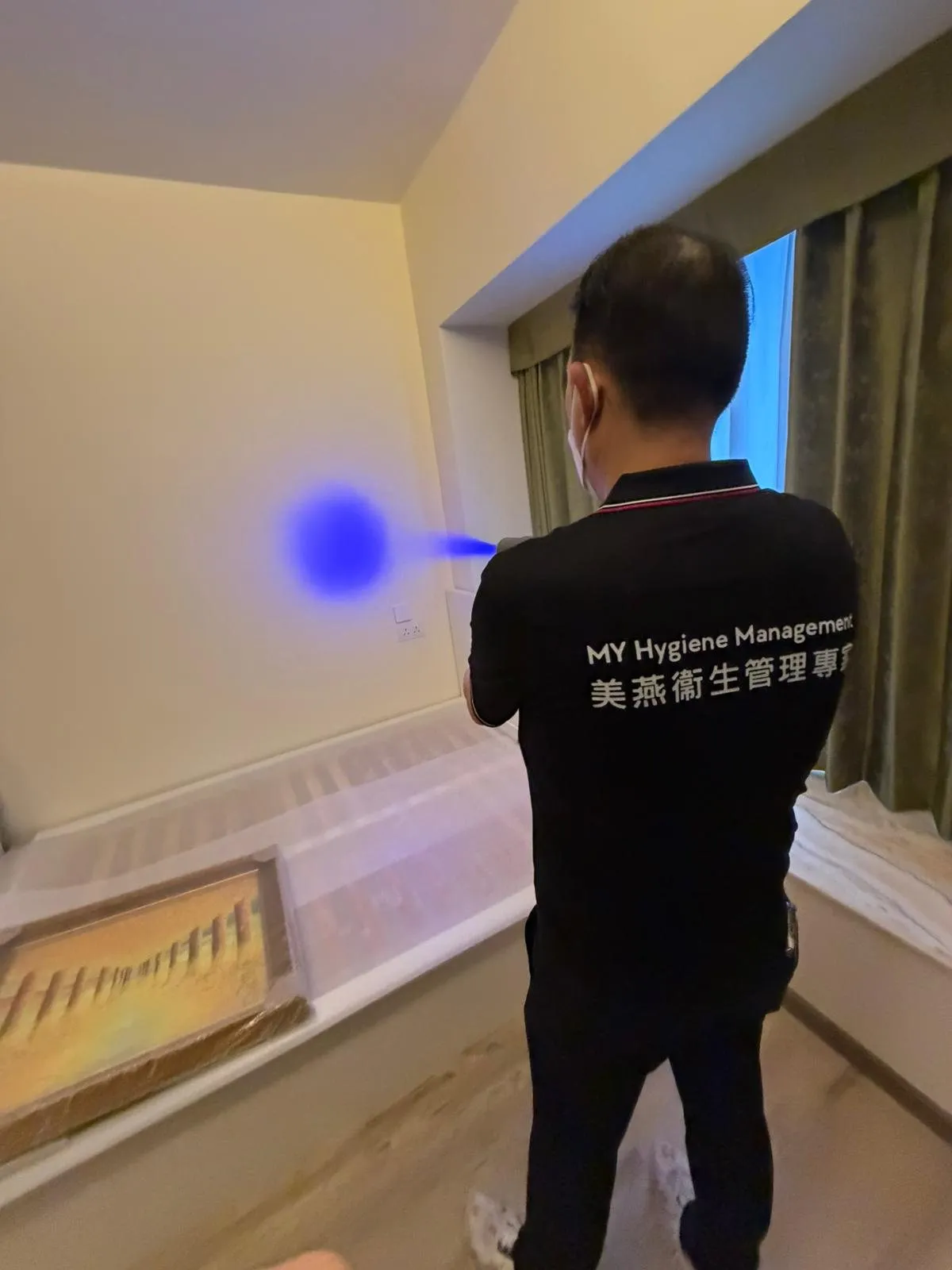 美燕技術員穿著公司制服，以藍光噴塗機為住宅牆身進行除甲醛處理